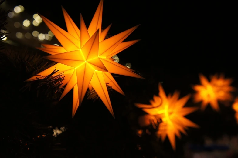 a group of yellow stars sitting on top of a christmas tree, by Stefan Gierowski, happening, beautiful lit lamps, the morning star, amber, soft white glow