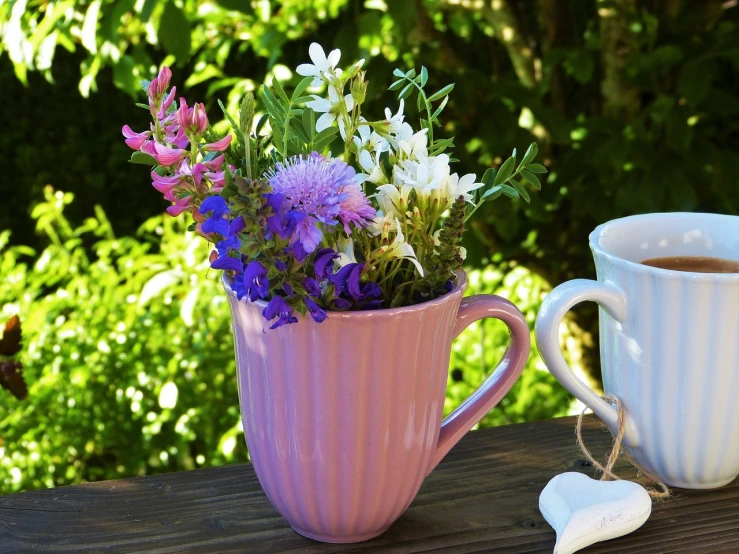 a cup of coffee and a vase of flowers on a table, a picture, romanticism, herbs and flowers, pink and purple, unique pot made for houseplants, picking up a flower