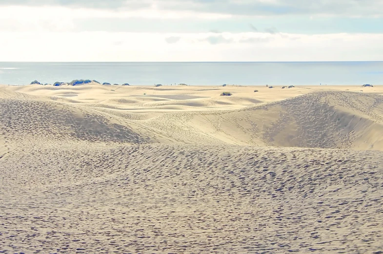 a man riding a snowboard on top of a sandy beach, a tilt shift photo, shutterstock, panorama, majestic dunes, big island, background image