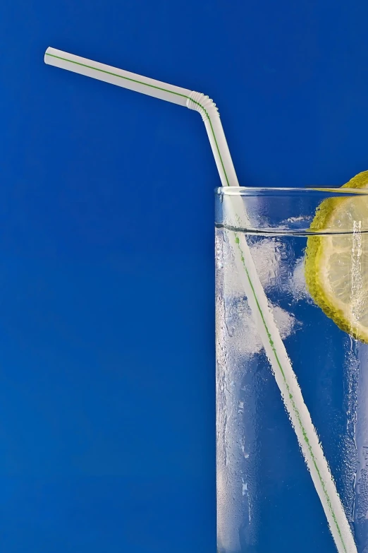 a glass of water with a slice of lemon and a straw, a picture, by Jan Rustem, minimalism, with a blue background, sparkling water, icey, angled