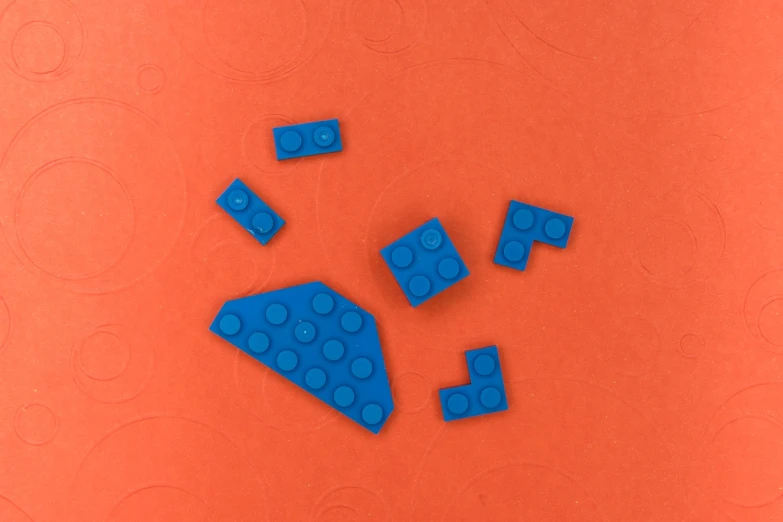 a group of blue legos sitting on top of an orange surface, inspired by Kazimir Malevich, suprematism, blue submarine no. 6, bottom - view, holes, miniature product photo