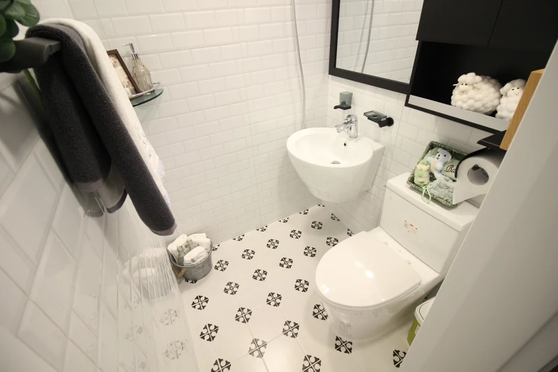 a white toilet sitting in a bathroom next to a sink, by Robbie Trevino, shutterstock, white and black color palette, small room in tokyo, mosaic floor, miffy