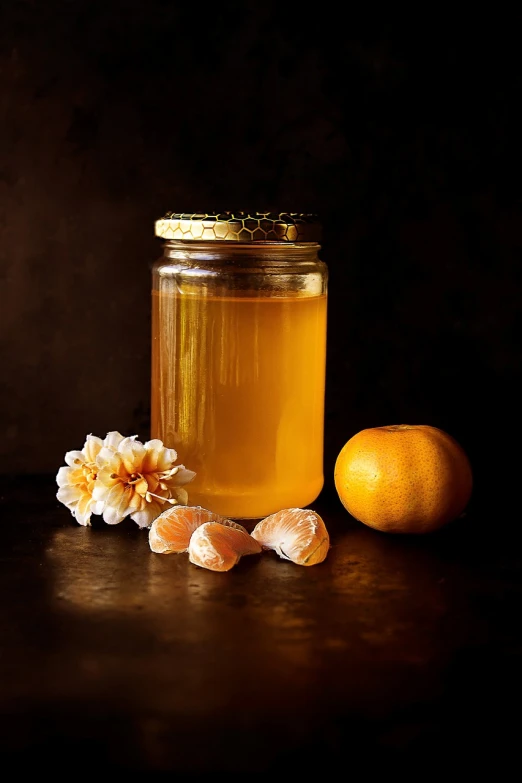 a jar of honey next to an orange on a table, a still life, by Aleksander Gierymski, pexels, renaissance, jelly - like texture. photograph, fruit and flowers, with a black background, highly detailed product photo