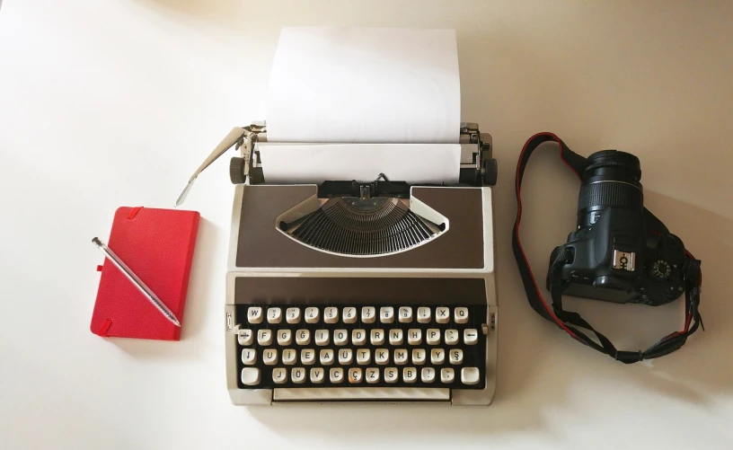 a typewriter sitting on top of a table next to a camera, a picture, figuration libre, aerial view from above, on a white background, journalist photo, advertising photo