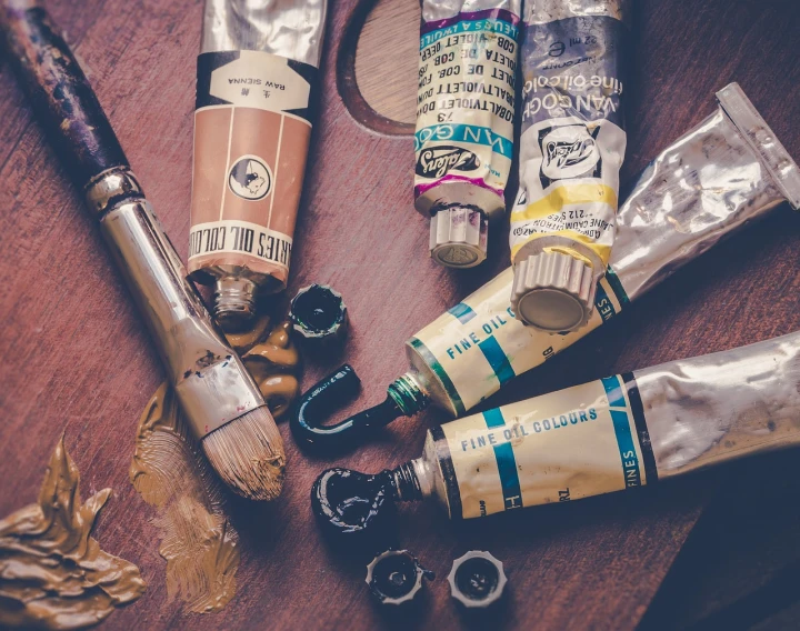 a group of paint tubes sitting on top of a wooden table, by Jakob Gauermann, pexels, visual art, vintage colours 1 9 5 0 s, intricate oil details, oil on canvas high angle view, anime vintage colors