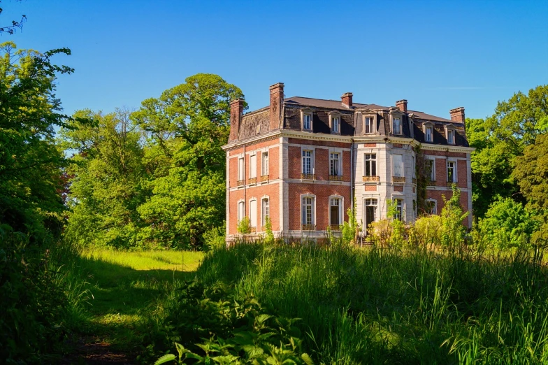 a large brick building sitting in the middle of a lush green field, a portrait, by Etienne Delessert, shutterstock, barbizon school, forgotten and lost in the forest, mansion, stock photo, remains