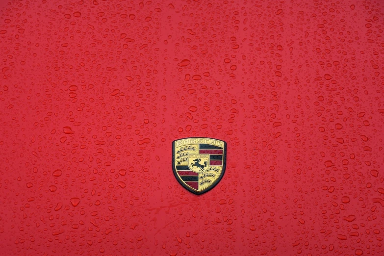 a close up of a porsche emblem on a red car, inspired by Bernardo Cavallino, postminimalism, rain is falling, 4k high res, detailed color scan, on a pale background