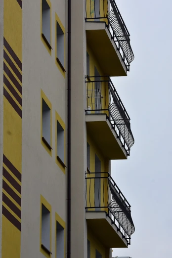 a tall building with balconies and balconies on the balconies, a photo, bauhaus, yellow details, a ghetto in germany, profile perspective, very accurate photo