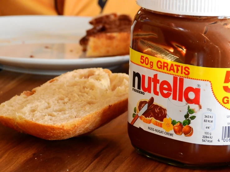 a jar of nutella next to a slice of bread, by Gina Pellón, the netherlands, ultrawide shot, promo, panini