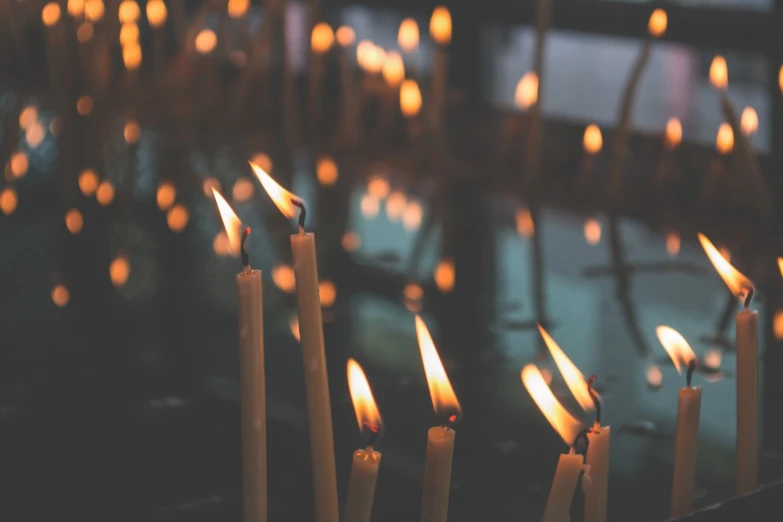 a group of lit candles sitting next to each other, a picture, by Matt Cavotta, shutterstock, retro effect, in a large cathedral, bokeh photo, floating candles