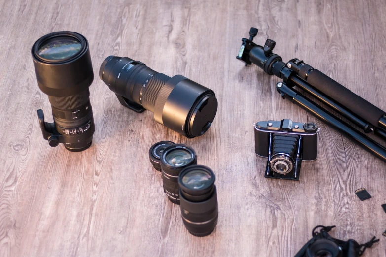 a group of cameras sitting on top of a wooden floor, a picture, by Aleksander Kotsis, 3 0 0 mm telephoto lens, 4 k product photo, various items, detailed product photo