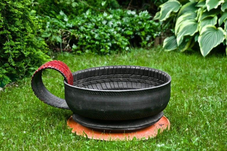 a large black bowl sitting on top of a patch of grass, by Jan Stanisławski, flickr, tire, black steel with red trim, tea cup, upcycled