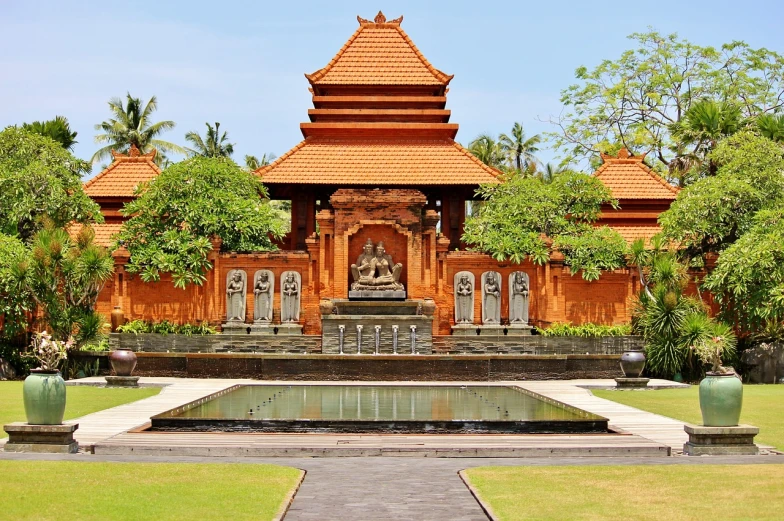 a large building with a fountain in front of it, a statue, by Bernardino Mei, shutterstock, sumatraism, red sandstone natural sculptures, bali, gate, tiled fountains