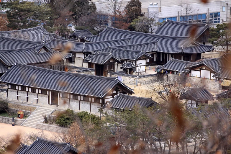 a group of buildings sitting on top of a lush green hillside, a tilt shift photo, inspired by Kim Hong-do, flickr, mingei, korean traditional palace, winter, [ closeup ]!!, view from high