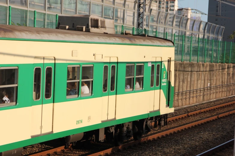 a green and white train traveling down train tracks, shin hanga, maintenance photo, detailed zoom photo