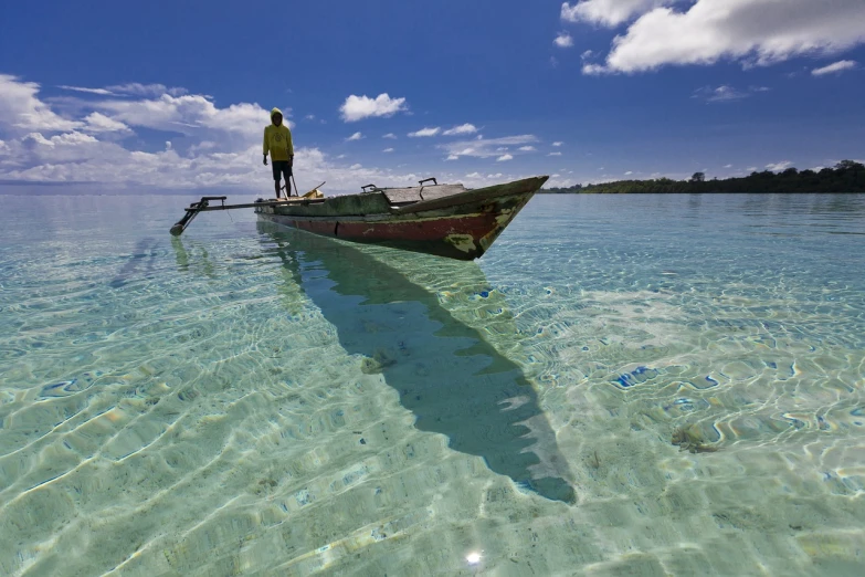 a man standing on top of a boat in the ocean, a picture, by Peter Churcher, flickr, sumatraism, standing in shallow water, reflections ray, tim hildebrant, stock photo