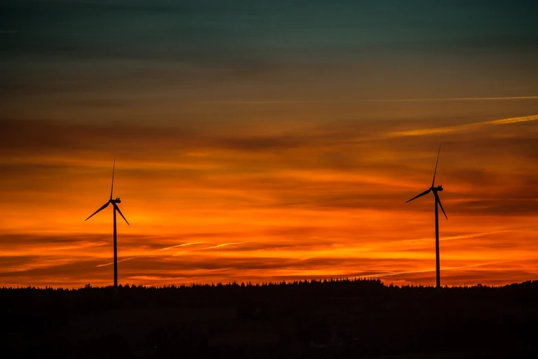 a couple of wind turbines sitting on top of a hill, by Stefan Gierowski, pexels contest winner, sunsetting color, black and orange, blog-photo, fades to the horizon