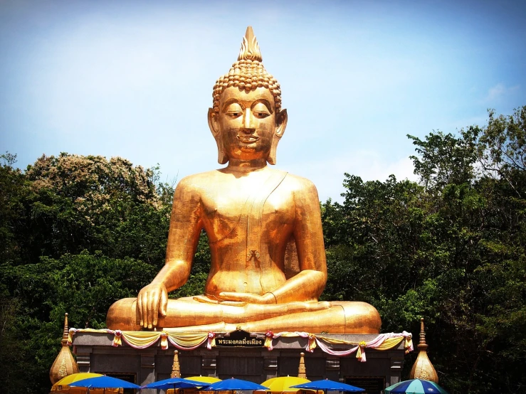 a large golden buddha statue sitting in the middle of a park, a statue, shiny skin”, high res photo