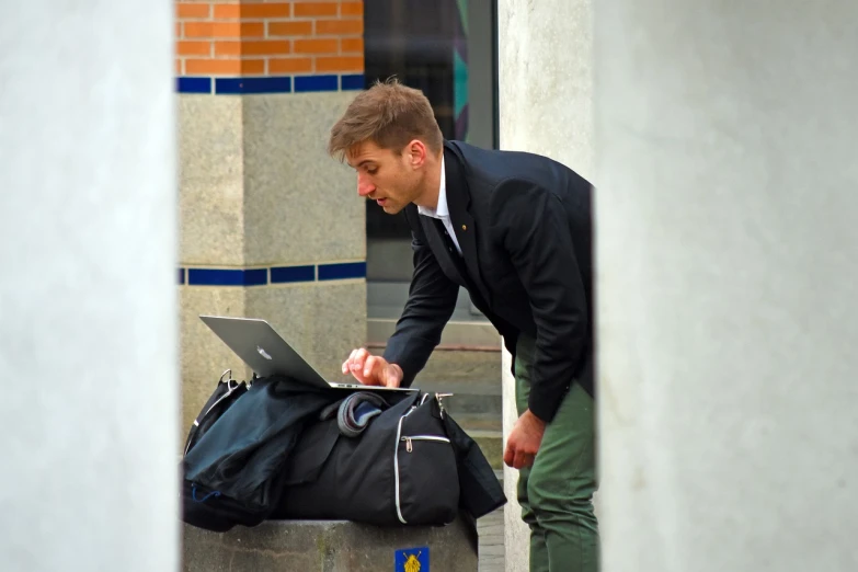 a man in a suit looking at a laptop, by Emma Andijewska, flickr, happening, with a backpack, street - level, college students, full colour