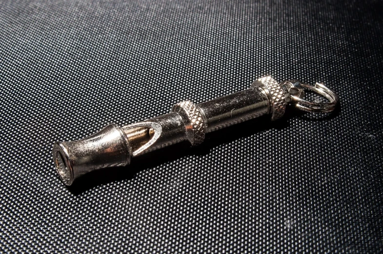 a close up of a metal object on a cloth, by Jason Felix, unsplash, hurufiyya, lightsaber, amulet, in style of chrome hearts, connector