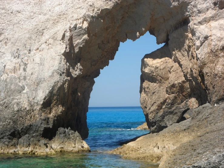 a large rock formation in the middle of a body of water, by Edward Corbett, shutterstock, looking through a portal, cyprus, july 2 0 1 1, nice weather