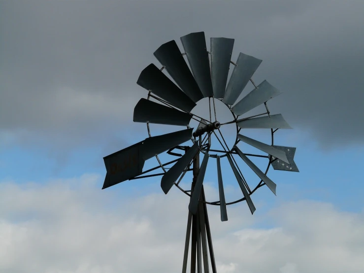 a windmill with a cloudy sky in the background, by Dennis Ashbaugh, flickr, kinetic art, australian, grey mist, profile, stern