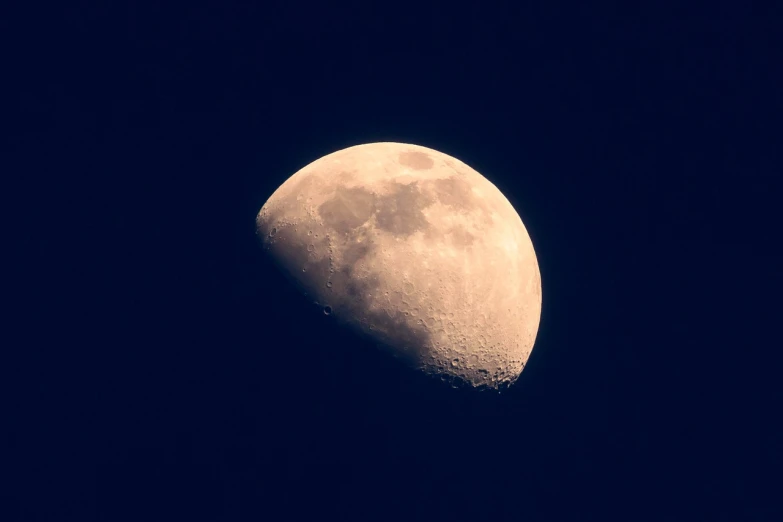 the moon is lit up in the dark blue sky, a macro photograph, inspired by John Moonan, flickr, halfmoon in space, taken through a telescope, craters, istock