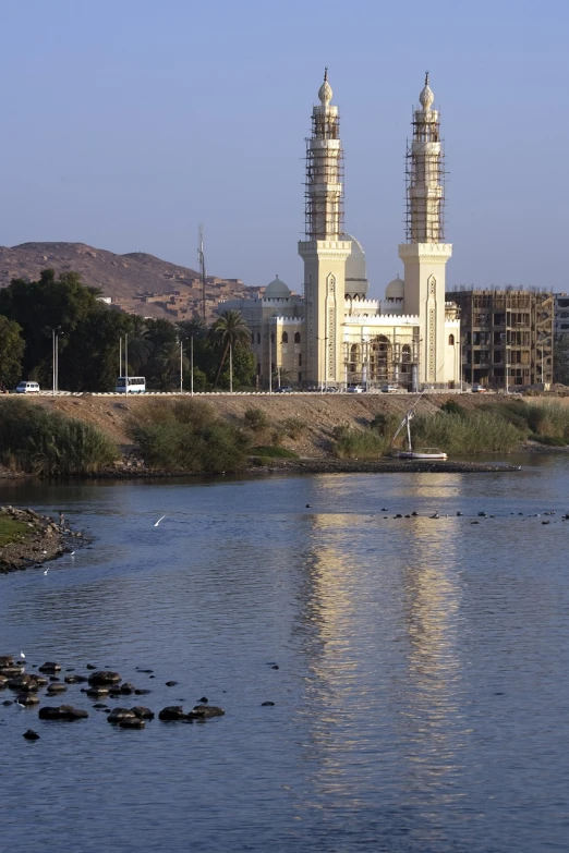 a large white building next to a body of water, hurufiyya, nile river environment, two towers, gold, chambliss giobbi