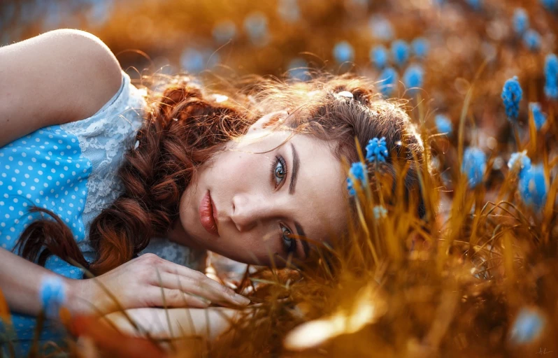 a woman laying in a field of blue flowers, by Galen Dara, pixabay contest winner, orange and brown leaves for hair, karol bak uhd, attractive brown hair woman, andrey gordeev