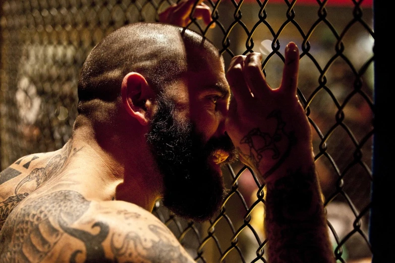 a man with a beard standing in front of a fence, a tattoo, flickr, epic mma fight, wonderful scene, brown buzzcut, cages