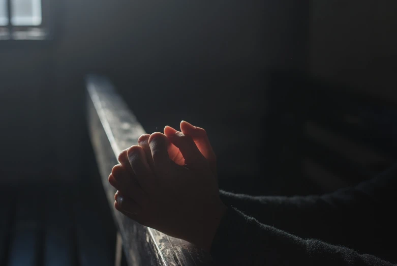 a close up of a person's hands on a railing, kneeling in prayer, light dark, a wooden, basic photo