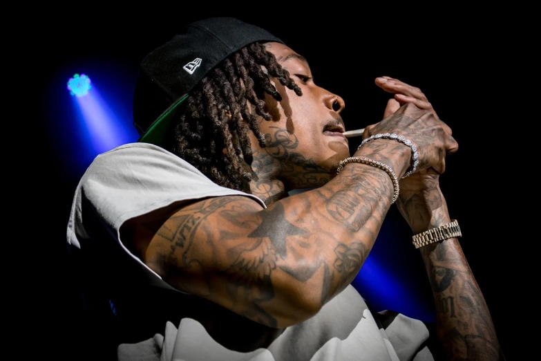 a close up of a person holding a microphone, a tattoo, by Willy Bo Richardson, wiz khalifa, focused on neck, mana shooting from his hands, serene expression