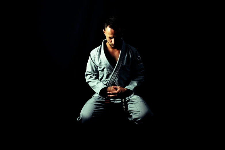 a man sitting on a stool in the dark, a portrait, inspired by Kanō Tanshin, minimalism, white belt, professional foto, mma, american veteran gi