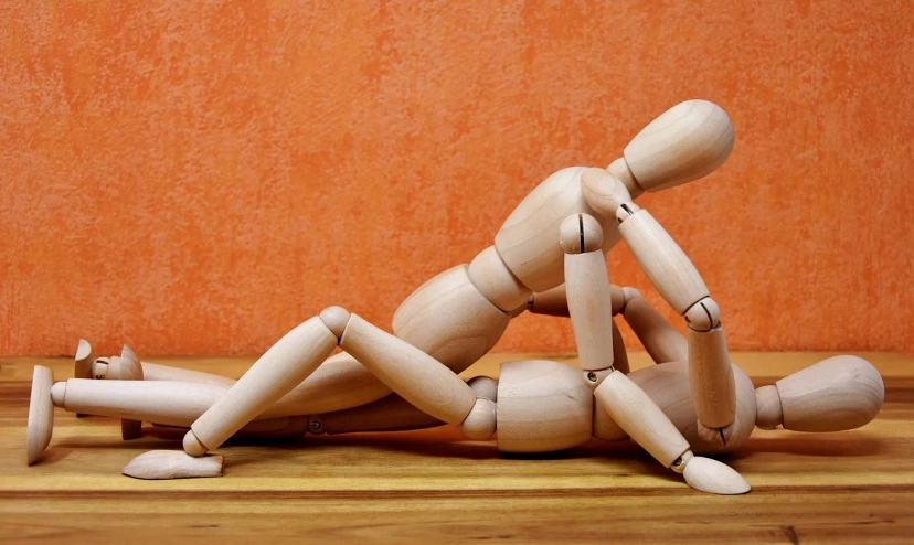 a wooden mannequin sitting on top of a wooden floor, a picture, man grabbing a womans waist, articulated joints, laying on their back, stick figure