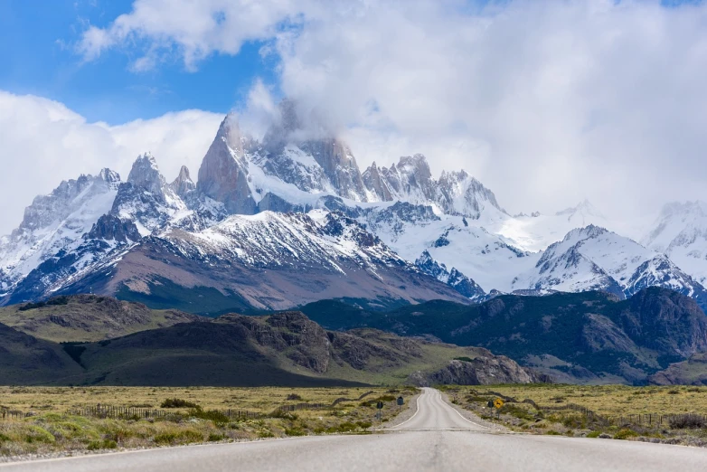 a dirt road with a mountain in the background, shutterstock, patagonian, snowy craggy sharp mountains, tall spires, front view dramatic