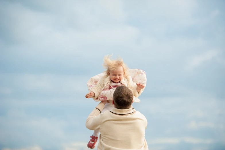 a man holding a little girl up in the air, by Hristofor Zhefarovich, shutterstock, windy weather, blond hair with pigtails, modern high sharpness photo, stock photo