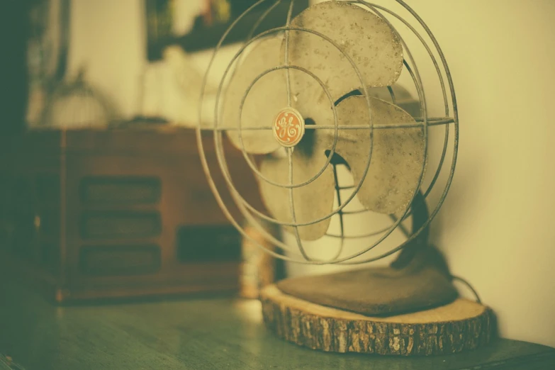 a fan sitting on top of a wooden table, unsplash, vintage style, shallow dof, old home decor, cooling