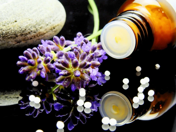 a bottle of essential oils next to a bunch of flowers, by Anna Haifisch, pixabay, process art, pills, on black background, lavender, molecules