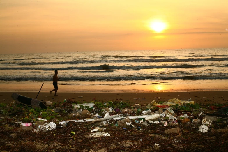 a person walking on a beach next to trash, plasticien, sun set, sri lankan landscape, some people around ”, kodak photo