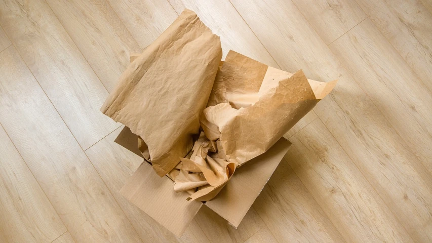 a brown paper bag sitting on top of a wooden floor, a stock photo, by Richard Carline, shutterstock, tissue paper art, delivering parsel box, seen from above, variations