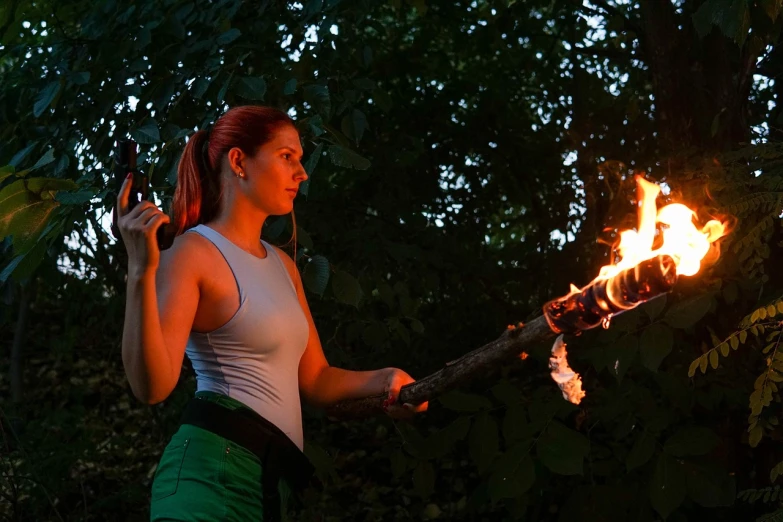 a woman holding a fire stick in her hand, a portrait, by Jan Rustem, flickr, glowing draconic staff, summer evening, green glow, holding a giant flail