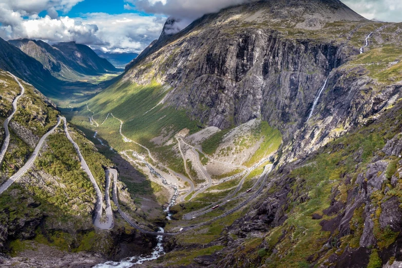 a winding mountain road in the middle of a valley, by Harald Giersing, multiple waterfalls, wide long view, chriss foss, full photo