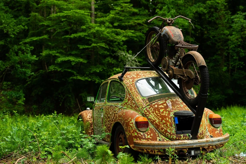 an old car with a motorcycle on top of it, a photo, by Dietmar Damerau, ecological art, beetle-inspired, camouflaged gear, 🦩🪐🐞👩🏻🦳, german forest