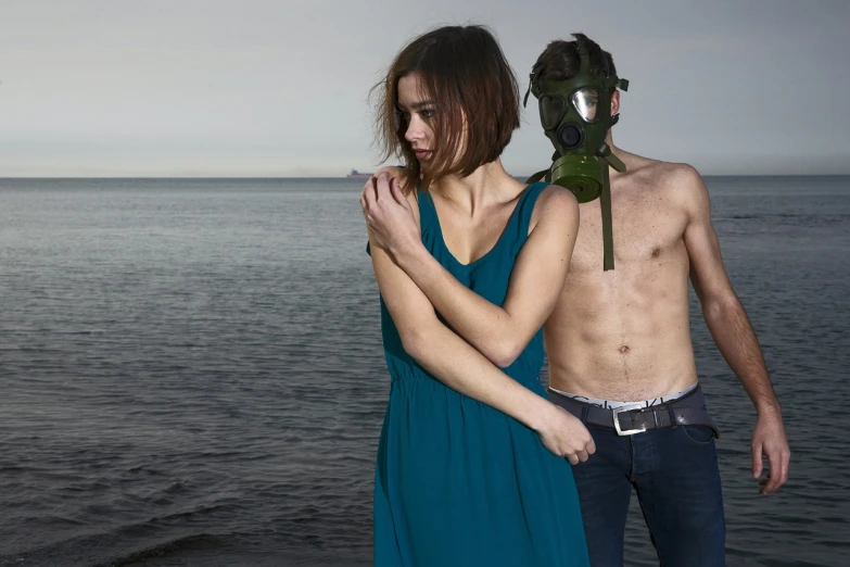 a woman in a blue dress standing next to a man in a gas mask, a photo, by Eva Gonzalès, tumblr, romanticism, bikini + tattered military gear, marat zakirov, green facemask, hybrid human/tank