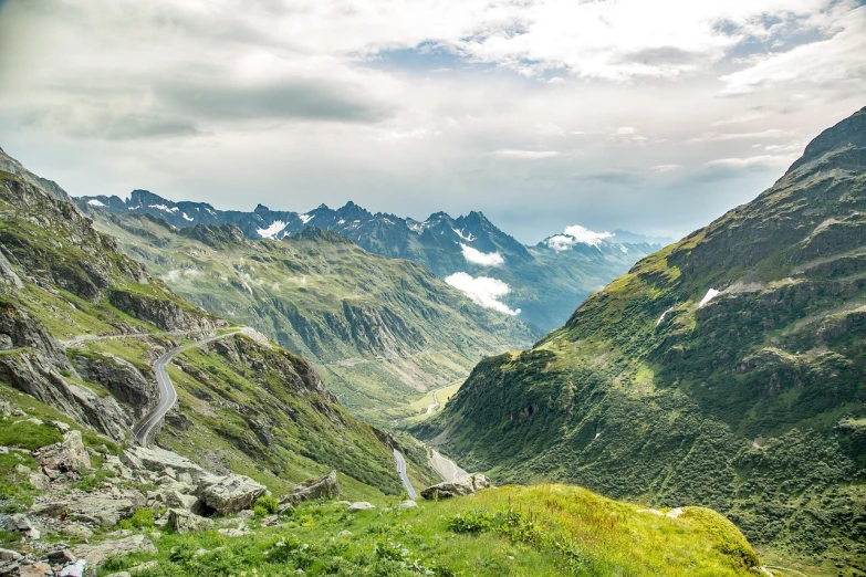 a group of people standing on top of a lush green hillside, a stock photo, by Werner Andermatt, shutterstock, les nabis, road between hills, glacier landscape, in the swiss alps, wide long view