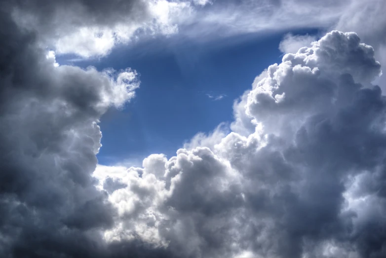 a plane flying through a cloudy blue sky, a photo, by Hans Schwarz, romanticism, big storm clouds, hdr detail, among heavenly sunlit clouds, in forcasted sky