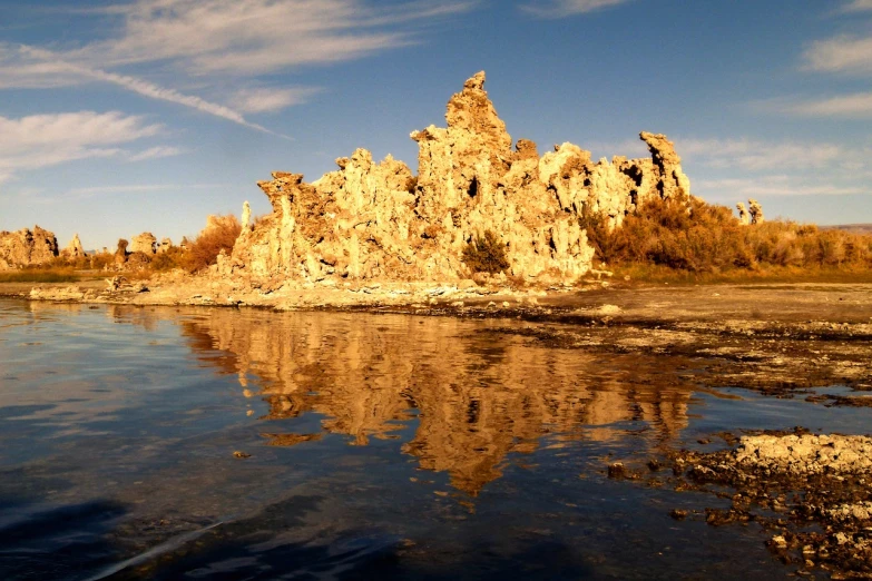 a body of water with rocks in the background, by Linda Sutton, flickr, romanticism, mammoth, lake reflection, chiseled formations, gooey