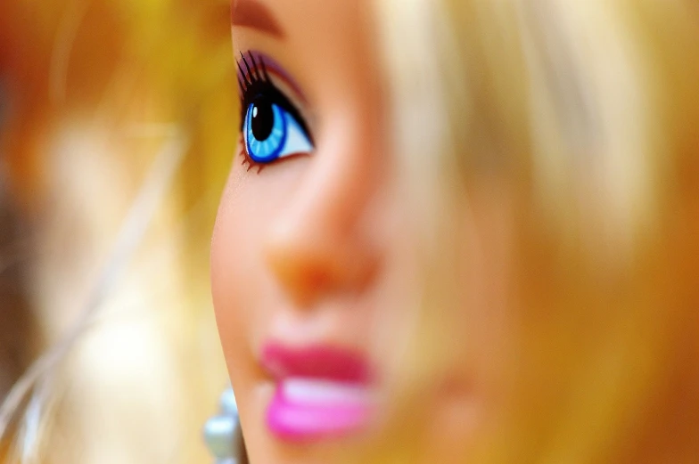 a close up of a barbie doll's face, a picture, by Tom Carapic, pixabay, half image, toy photo, she has a distant expression, with bright blue eyes