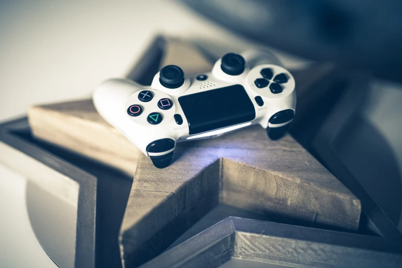 a video game controller sitting on top of a wooden table, a picture, by Matija Jama, glossy white, stars, playstation 4, blog-photo