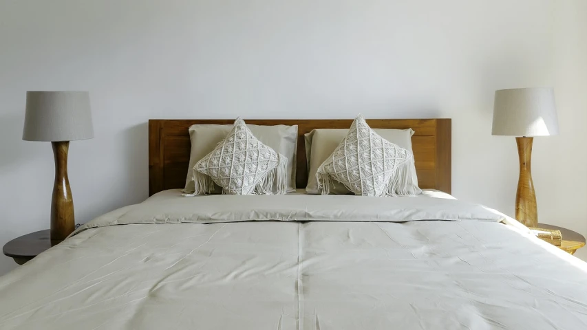 a bed with two pillows on top of it, by Konrad Witz, pexels, white walls, light beige pillows, with detailed wood, half and half